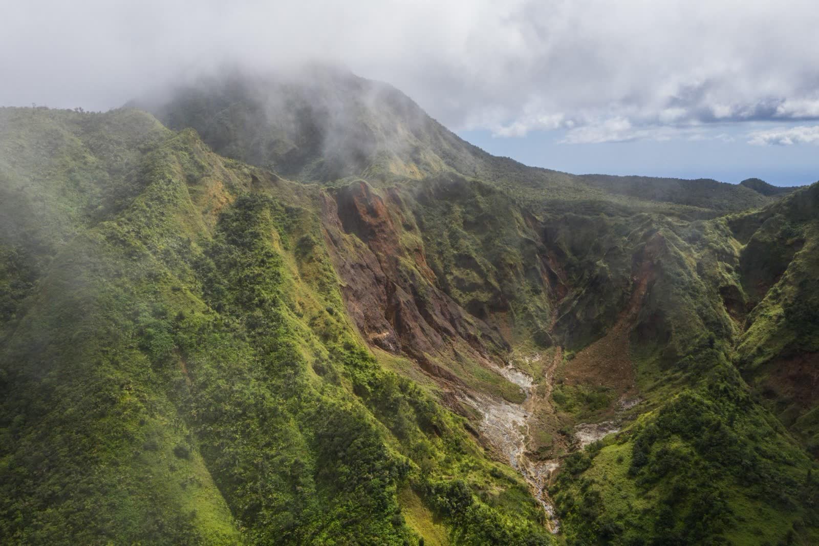 Aerial view of the Morne Trois Pitons rainforest with the Valley of Desolation's volcanic slopes and the Roseau Valley beyond